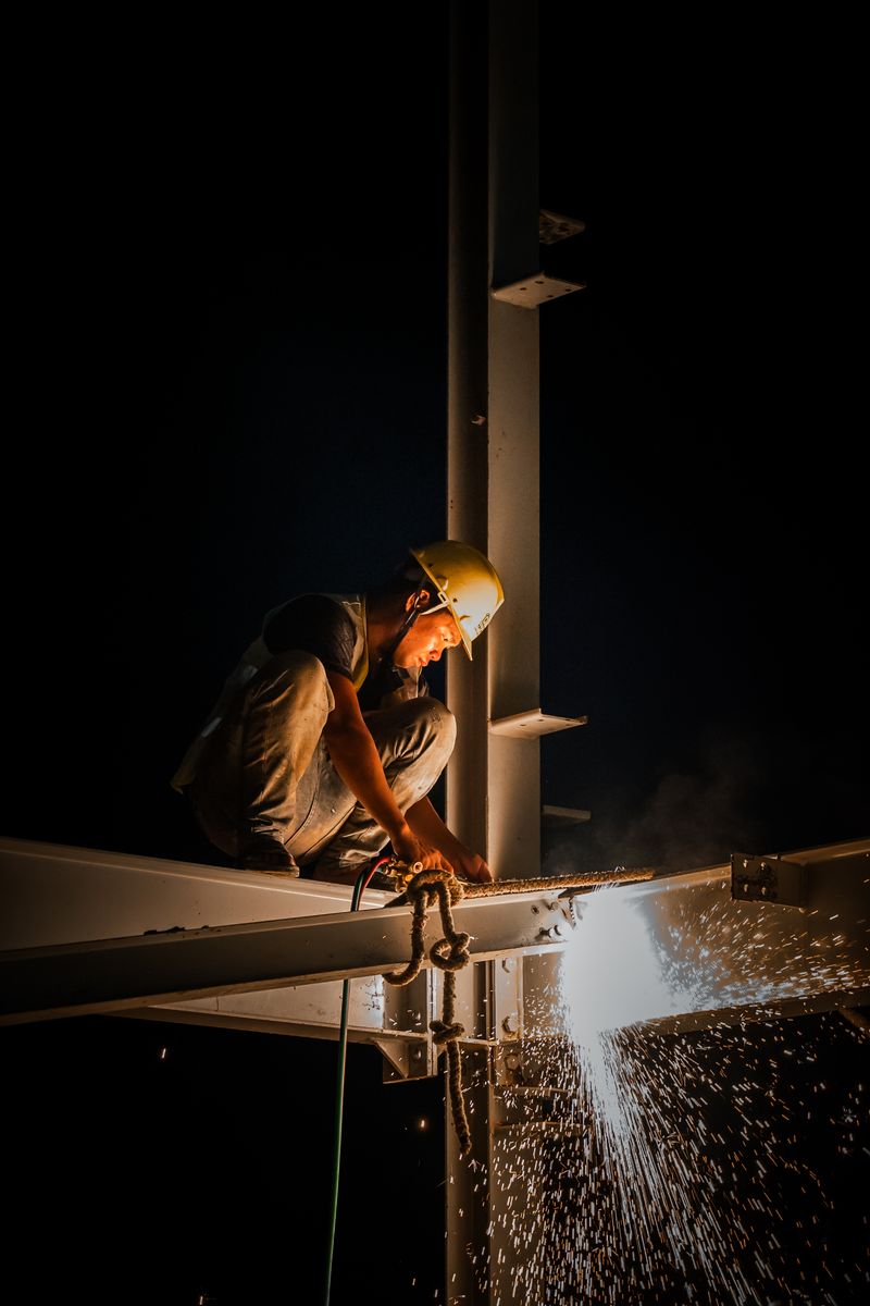 Welder working on a steel structure with sparks at night