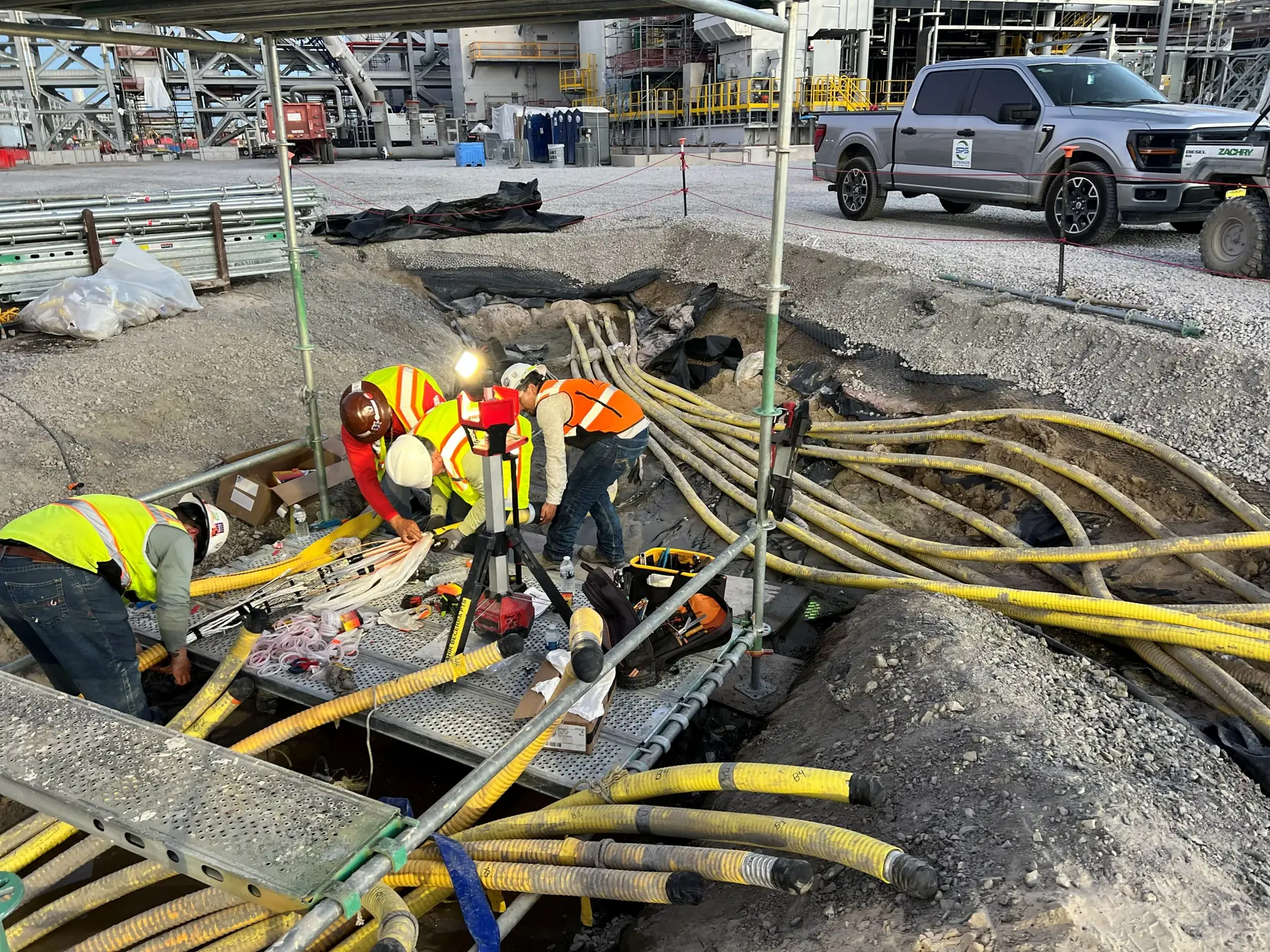 Sitewide electricians installing medium-voltage cable in an open trench on site